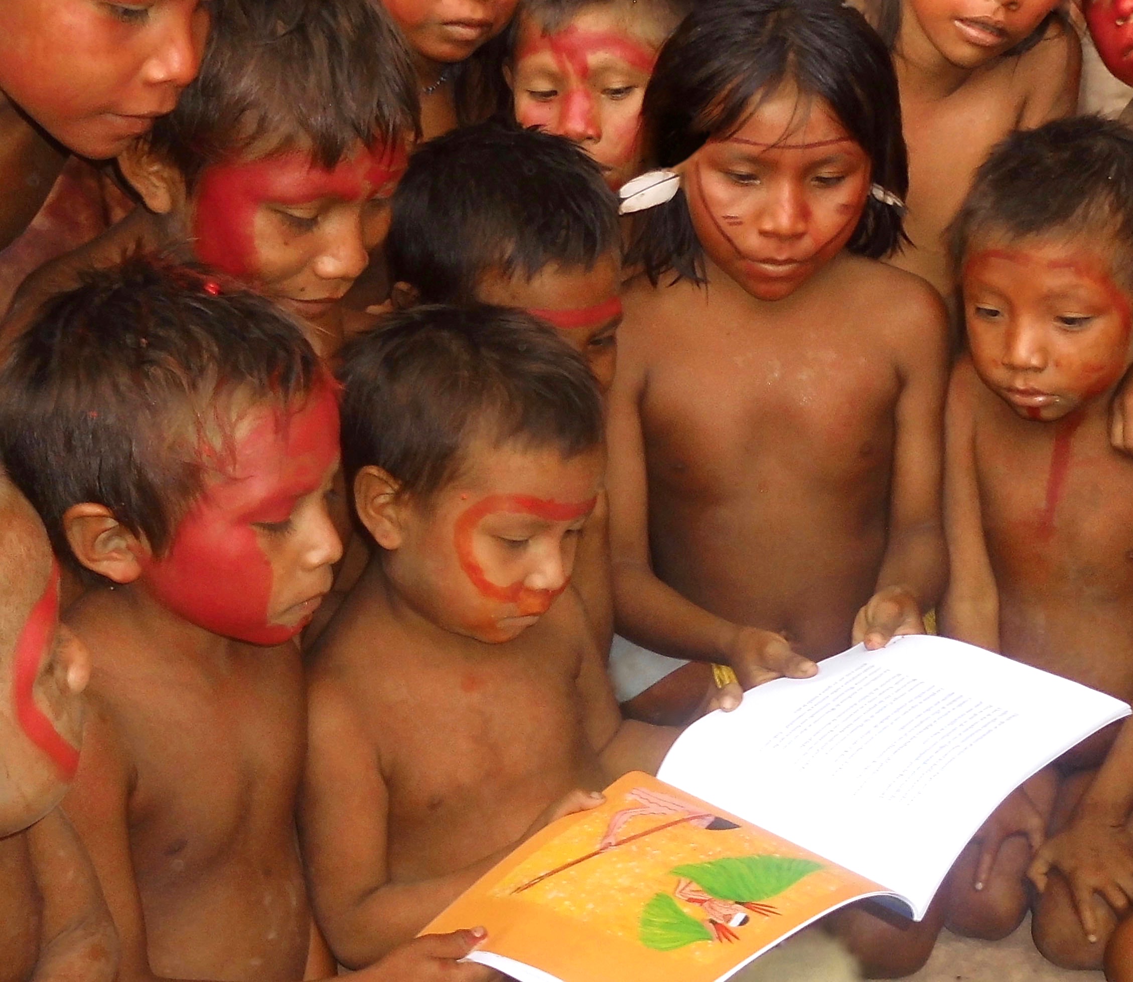Yanomami children with achiote face paint reading the Rainforest Magic book Vol. 1 by Barbara Crane Navarro