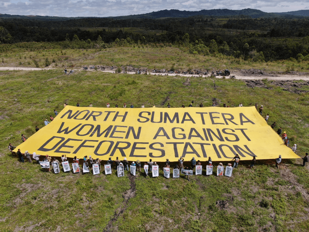 Indigenous Batak communities in North Sumatra hold a giant banner in protest of unresolved land conflicts and deforestation on Indigenous lands by PT. Toba Pulp Lestari. Photo by KSPPM, October 2022.

