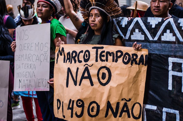 Protesters hold placards expressing their opinion during the demonstration. The Marco Temporal thesis, indigenous, and supporters of the indigenous movement met in downtown Rio de Janeiro, Brazil, in May 2023. ZUMA Press Inc / Alamy Stock Photo